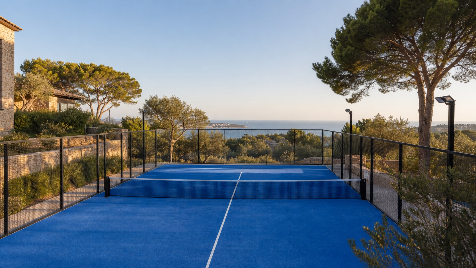 Padel-Court auf Mallorca mit Kalksteinmauer, Pinien, Blick Richtung Palma-Bucht und Schlägern auf der Bank